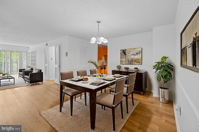 dining space featuring a chandelier, light wood-style floors, and baseboards