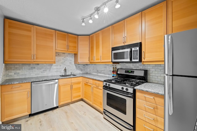 kitchen featuring appliances with stainless steel finishes, light wood-type flooring, a sink, and light brown cabinets