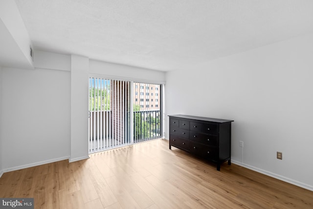 unfurnished room with light wood-style flooring and baseboards