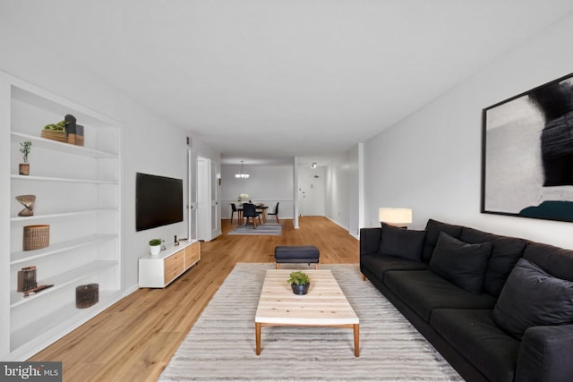 living room with light wood finished floors, built in features, and baseboards