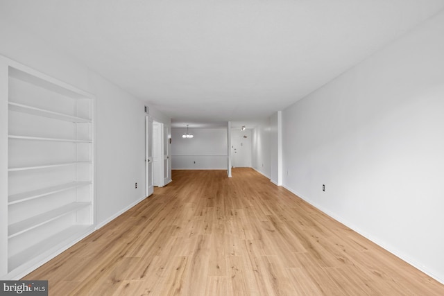 unfurnished room featuring light wood finished floors, baseboards, and a chandelier