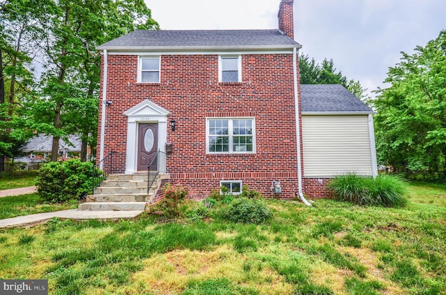 7009 Adelphi Rd, Hyattsville, MD 20782 - view of front facade with a chimney, brick siding, a front lawn, and roof with shingles