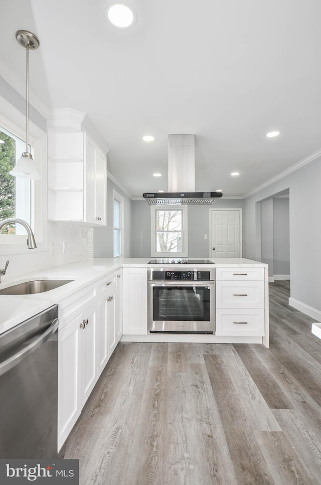 7009 Adelphi Rd, Hyattsville, MD 20782 - kitchen featuring island range hood, appliances with stainless steel finishes, a sink, ornamental molding, and a peninsula