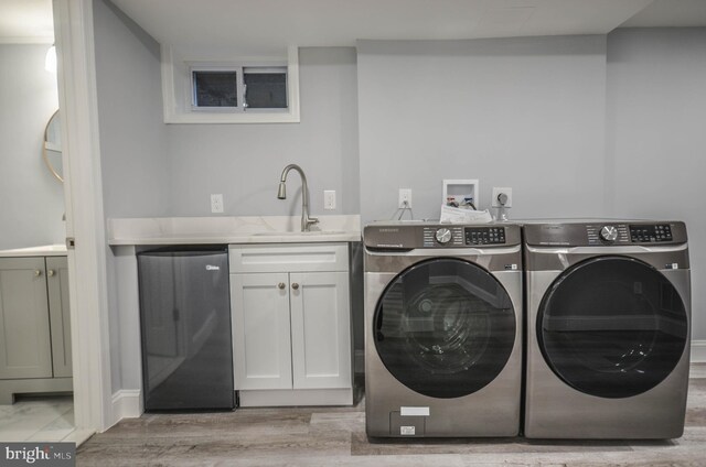 7009 Adelphi Rd, Hyattsville, MD 20782 - clothes washing area featuring washing machine and clothes dryer, cabinet space, and light wood-style floors