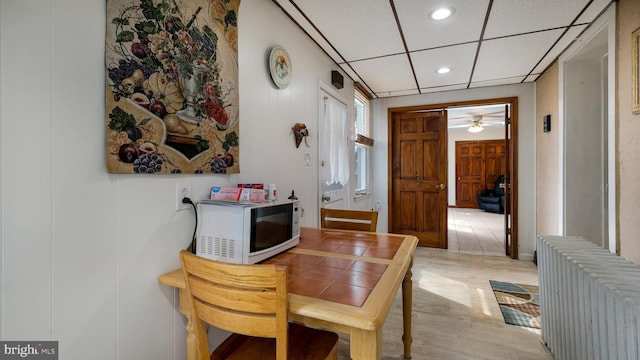 dining room with a ceiling fan, radiator heating unit, light wood-type flooring, recessed lighting, and a drop ceiling