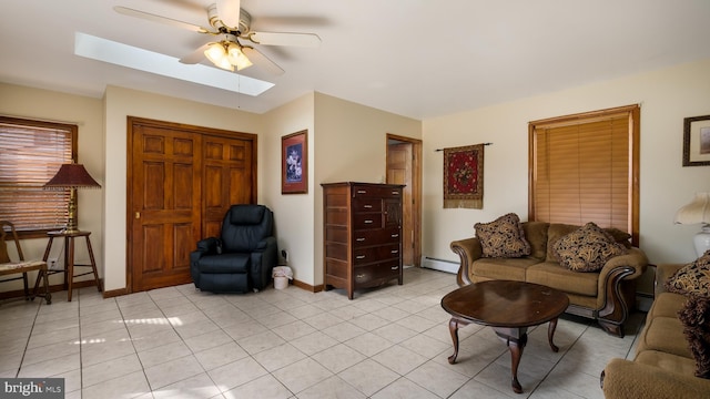 living room featuring a skylight, a ceiling fan, a baseboard heating unit, light tile patterned flooring, and baseboards