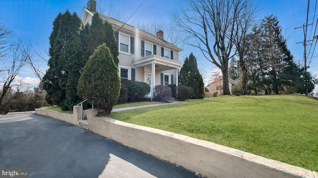view of property exterior with a chimney and a lawn