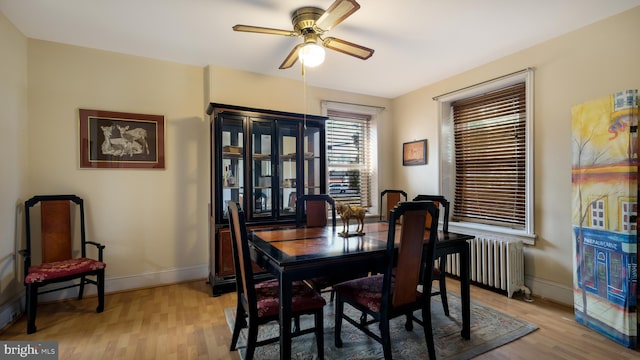 dining room with radiator heating unit, a ceiling fan, light wood-style flooring, and baseboards