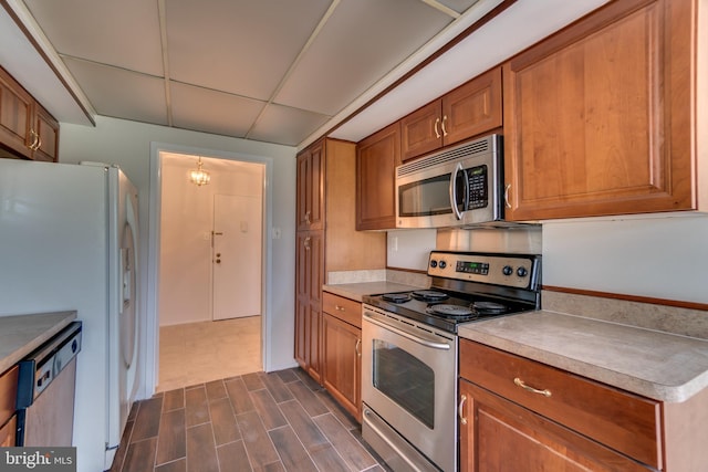 10300 Bushman Dr Unit 209, Oakton, VA 22124 - kitchen featuring stainless steel appliances, brown cabinetry, a drop ceiling, light countertops, and dark wood-style floors