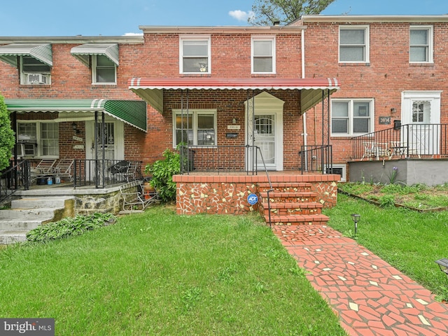 view of property with brick siding, a porch, and a front lawn