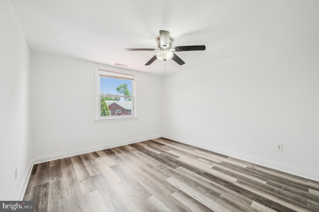 empty room with ceiling fan, wood finished floors, and baseboards