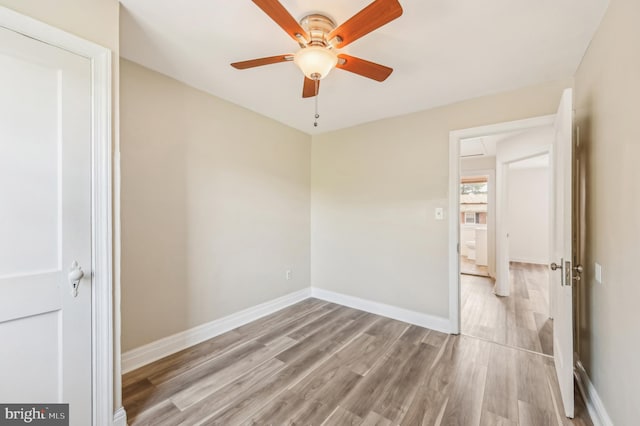 empty room with wood finished floors, a ceiling fan, and baseboards