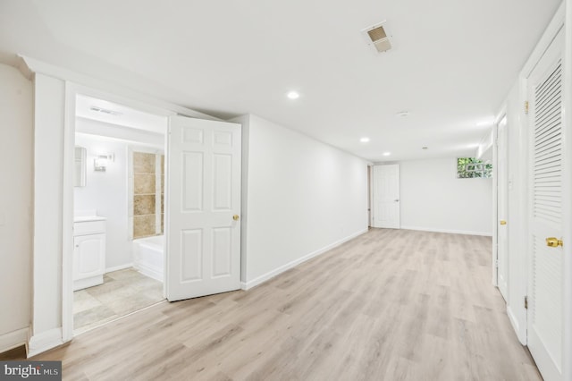 finished below grade area featuring light wood finished floors, recessed lighting, and baseboards