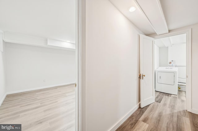 hallway featuring washer / clothes dryer, light wood-style flooring, and baseboards