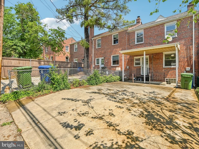 rear view of property with brick siding, a chimney, and fence