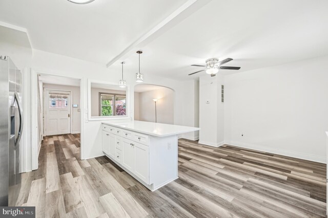 kitchen with a peninsula, stainless steel fridge, light wood finished floors, light countertops, and a ceiling fan