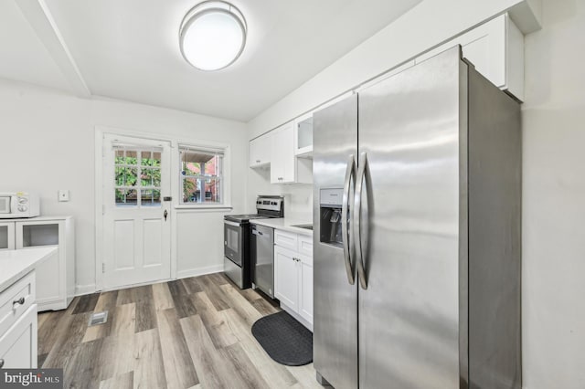 kitchen with appliances with stainless steel finishes, white cabinetry, light wood finished floors, and light countertops