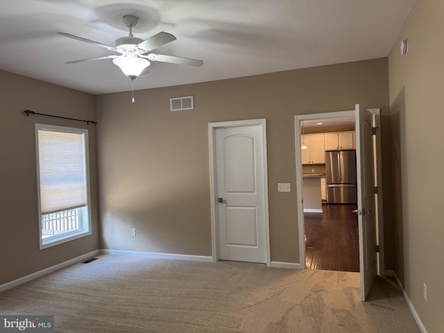 unfurnished bedroom with freestanding refrigerator, carpet flooring, and baseboards