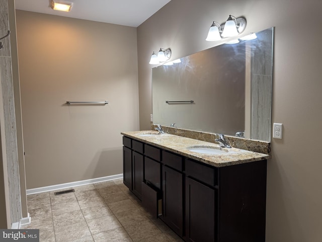 full bathroom featuring baseboards, double vanity, and tile patterned floors