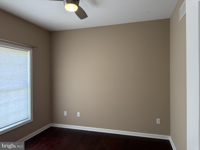 empty room with healthy amount of natural light, a ceiling fan, dark wood finished floors, and baseboards