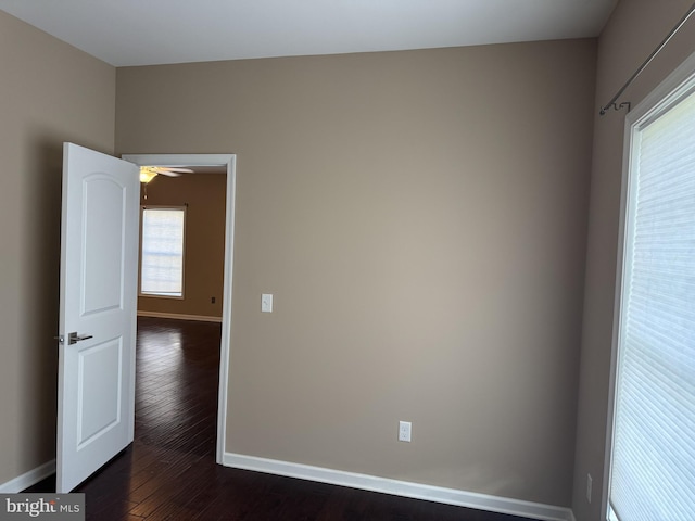 unfurnished room with baseboards, dark wood-style floors, and ceiling fan