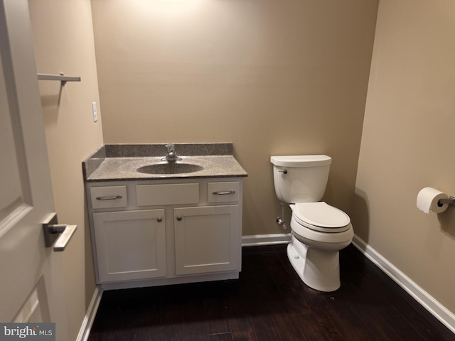 bathroom featuring vanity, toilet, baseboards, and wood finished floors