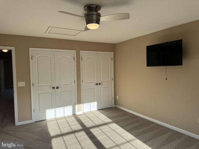 unfurnished bedroom with carpet flooring, multiple closets, and baseboards