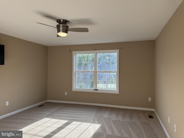 carpeted spare room with a ceiling fan and baseboards