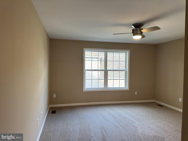 carpeted spare room featuring a ceiling fan and baseboards