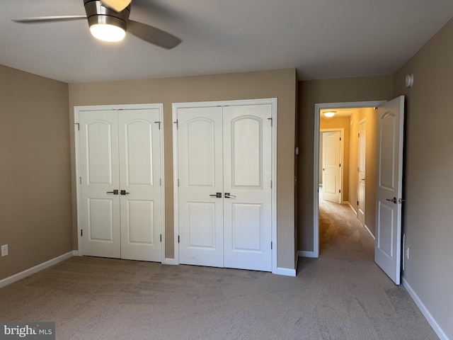 unfurnished bedroom featuring two closets, carpet, baseboards, and ceiling fan