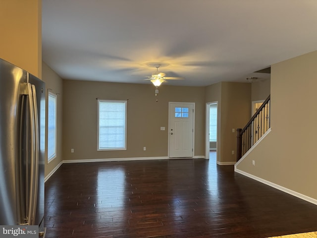 foyer entrance with a ceiling fan, dark wood-style flooring, baseboards, and stairs