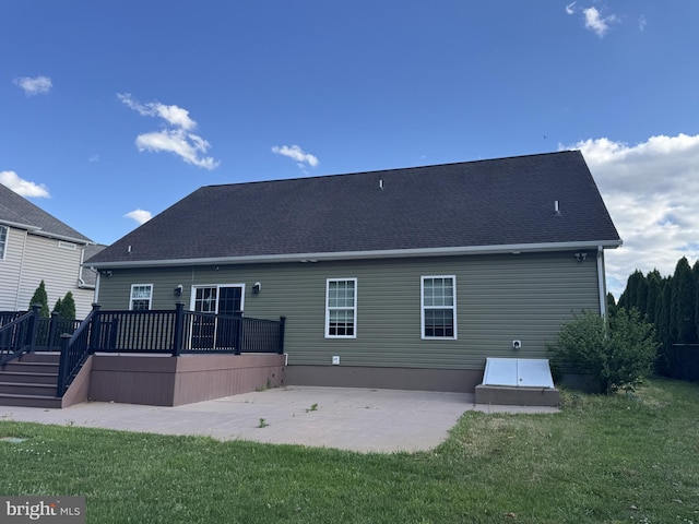 back of property featuring a wooden deck, a lawn, and a patio area
