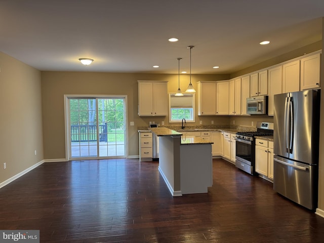 kitchen featuring stainless steel appliances, a sink, dark wood-style flooring, a kitchen island, and recessed lighting