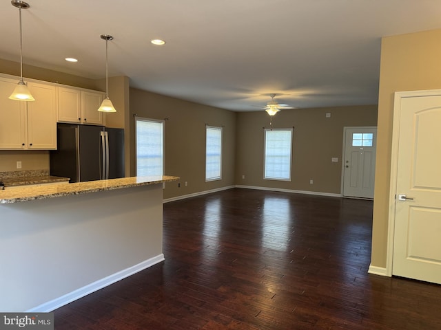 kitchen with freestanding refrigerator, ceiling fan, baseboards, light stone countertops, and white cabinetry
