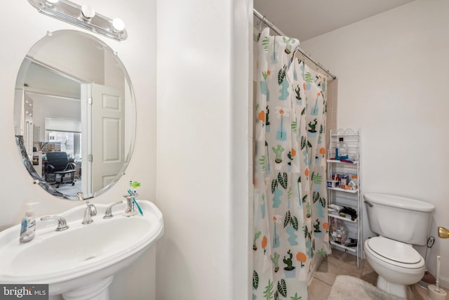bathroom featuring a sink, toilet, tile patterned flooring, and curtained shower