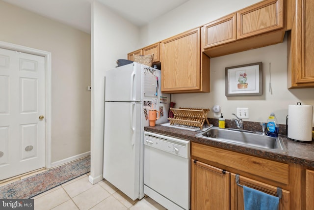 kitchen featuring white appliances, dark countertops, a sink, and light tile patterned floors