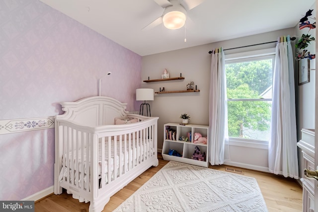 20932 Cox Mills Ct, Ashburn, VA 20147 - bedroom featuring wallpapered walls, a nursery area, multiple windows, light wood-style floors, and ceiling fan