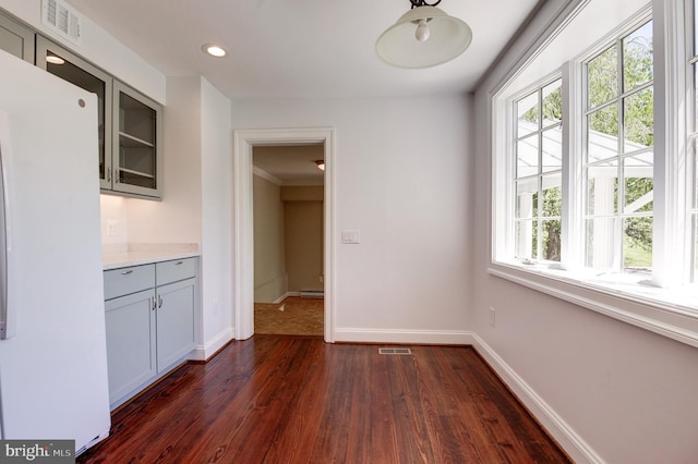 unfurnished dining area with dark wood finished floors, baseboards, recessed lighting, and ornamental molding