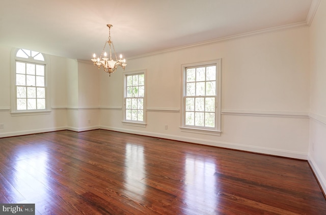 empty room featuring dark wood-style flooring, a chandelier, crown molding, and baseboards