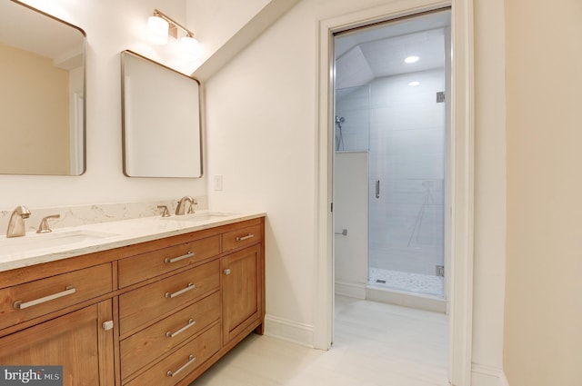 bathroom featuring a stall shower, double vanity, and baseboards