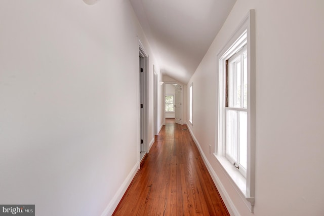 corridor with baseboards, wood finished floors, and lofted ceiling
