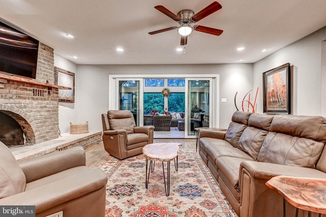 living area with wood finished floors, a ceiling fan, recessed lighting, and a fireplace