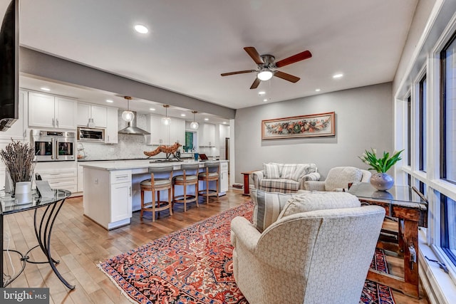 living area with ceiling fan, light wood finished floors, and recessed lighting