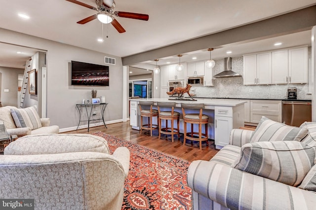 living area featuring wood finished floors, ceiling fan, baseboards, and recessed lighting