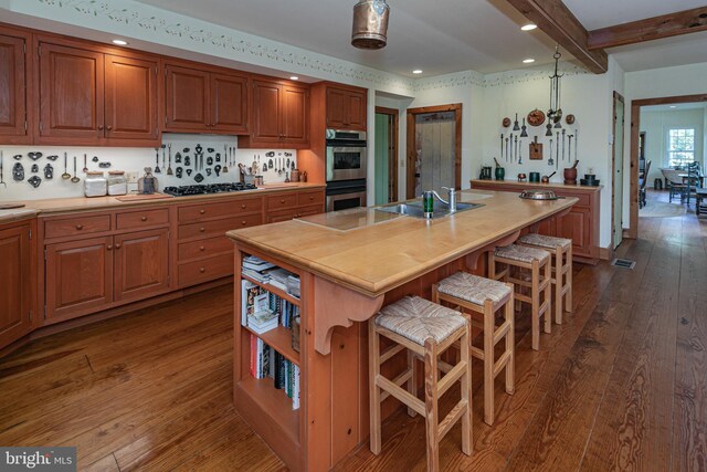 348 Rosemont Ringoes Rd, Stockton, NJ 08559 - kitchen featuring stainless steel double oven, a sink, dark wood-type flooring, a center island with sink, and a breakfast bar