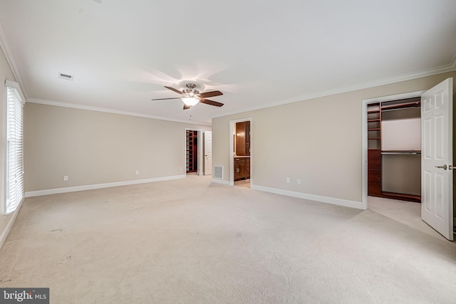 unfurnished bedroom with a walk in closet, crown molding, a closet, multiple windows, and light colored carpet