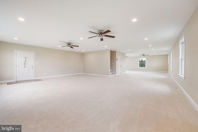 unfurnished living room featuring a ceiling fan, recessed lighting, light carpet, stairway, and baseboards