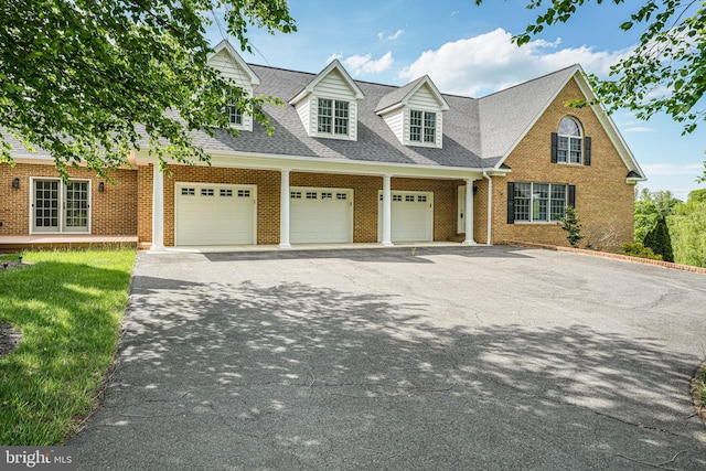 view of front of house featuring a garage, driveway, brick siding, and roof with shingles