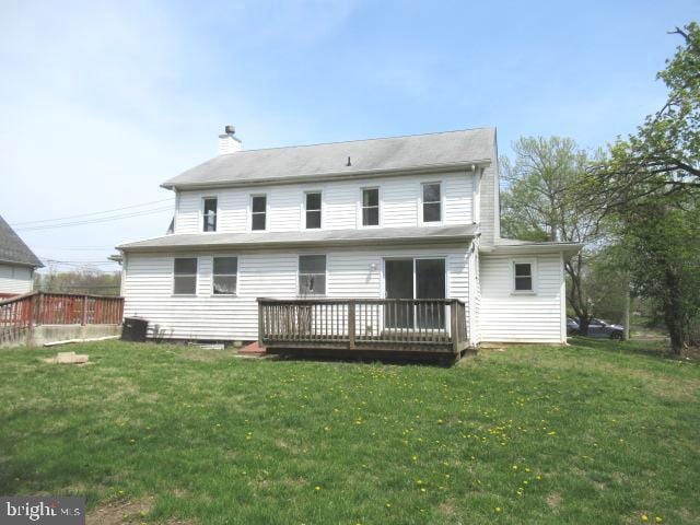rear view of property with a deck, a yard, and a chimney