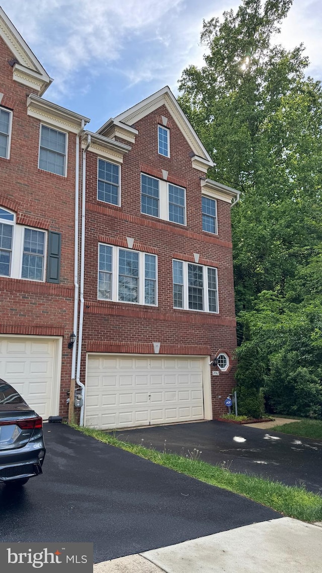 view of property featuring driveway, a garage, and brick siding